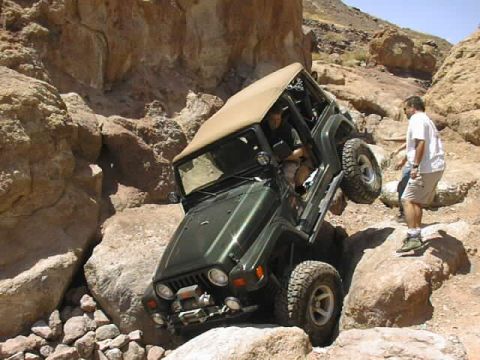 1997 Ford Ranger - A green Jeep Wrangler maneuvers through a challenging rocky terrain in a desert canyon.