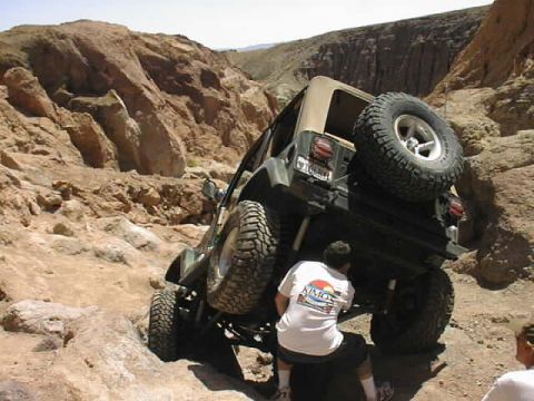 1997 Ford Ranger - A Jeep Wrangler tackles a challenging off-road trail, with a person observing the vehicle's progress.