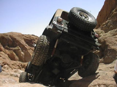 1997 Ford Ranger - Off-roading Jeep Wrangler tilted on a steep, rocky incline under a clear blue sky.