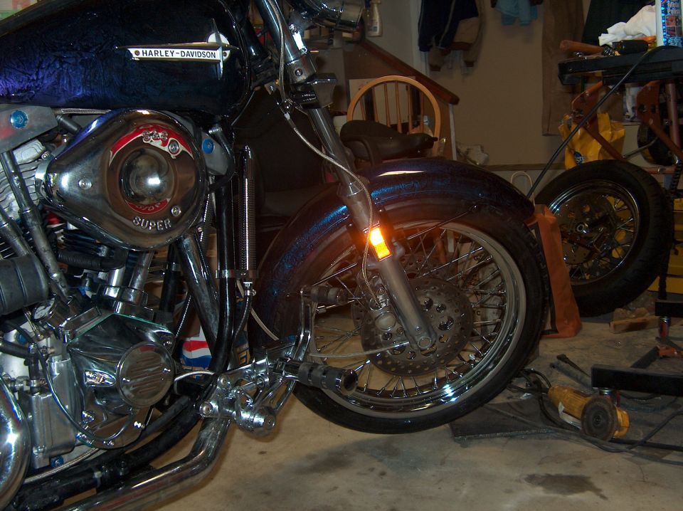 Blue Harley-Davidson front end in garage: chrome engine, spoke wheel, drilled rotor