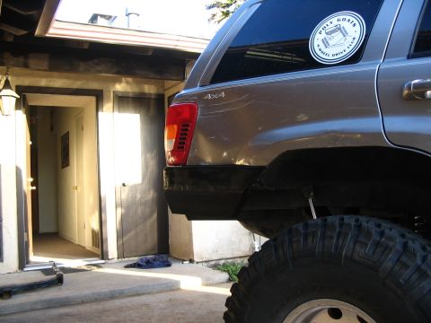 1999 Jeep Grand Cherokee - The rear of a Jeep Grand Cherokee is shown parked in a driveway next to a house.
