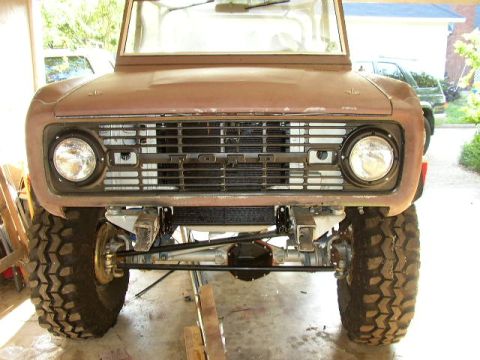 1995 Ford Bronco - Front view of a brown Ford Bronco, a black grille and large off-road tires, possibly undergoing restoration.