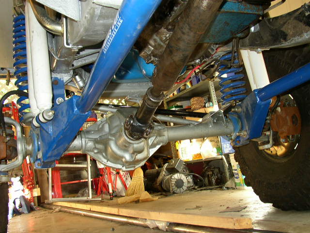 Close-up of blue suspension arms, driveshaft, and differential on a modified vehicle