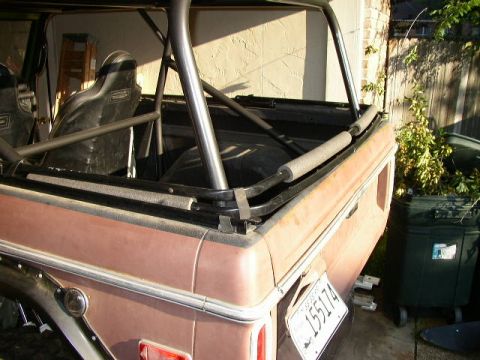 1995 Ford Bronco - The interior of a vehicle is visible, a roll cage and bucket seats, with a license plate in the foreground.