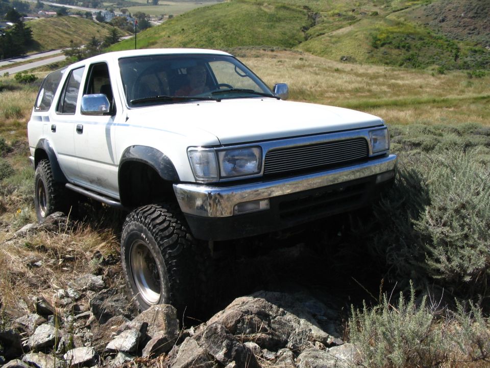 White lifted Toyota 4Runner with billet grille parked on rocky grassland slope