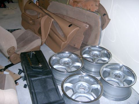 1996 Ford Probe - Interior car parts and wheels are gathered, possibly for restoration or replacement.