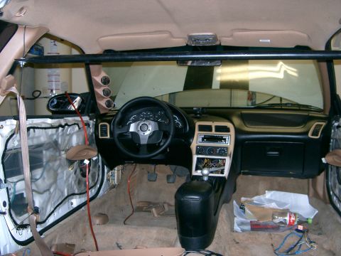 1996 Ford Probe - The interior of a 1996 Ford Probe shows modifications including a roll cage and aftermarket gauges, with door panels removed.