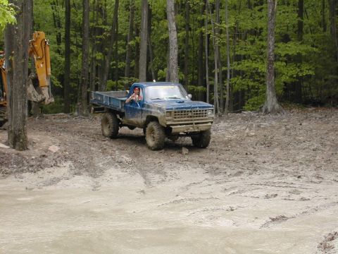1979 Ford Bronco - Pickup truck navigating a muddy trail in a forest setting.