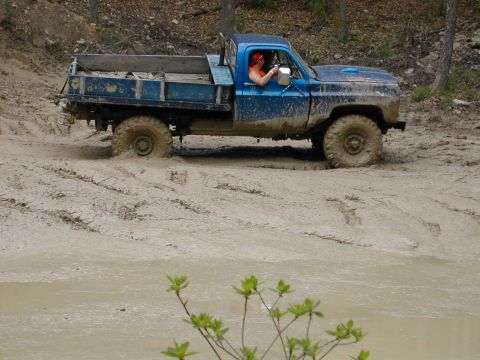 1979 Ford Bronco - This truck is deep in the mud, with its tires submerged and struggling to gain traction.