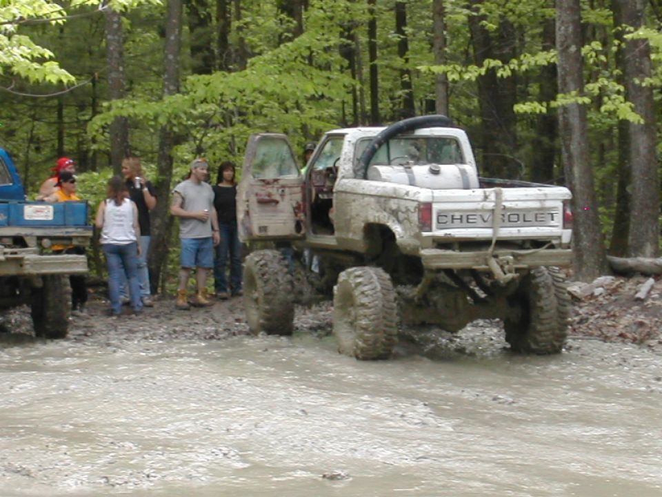 Muddy lifted pickup truck with 'CHEVROLET' on tailgate, rear view