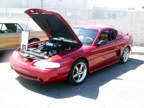 2002 Ford Mustang - Red Ford Mustang coupe with hood open, parked next to another vehicle.