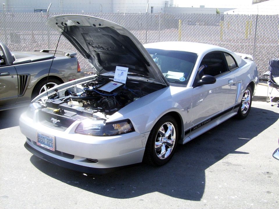 Silver 2002 Ford Mustang with hood open, showing engine and a sign