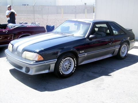 2002 Ford Mustang - A dark blue coupe with white racing stripes and silver trim is parked next to another vehicle.