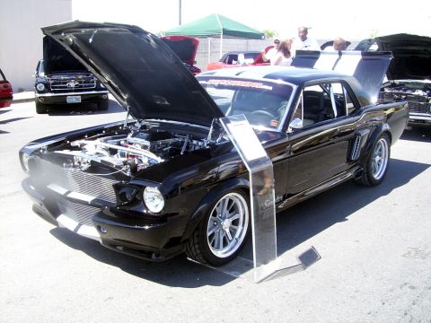 2002 Ford Mustang - A modified 1965 Ford Mustang is displayed with its hood and trunk open, revealing the engine and custom details.
