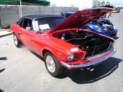 2002 Ford Mustang - A vintage red convertible is displayed with its hood open at an outdoor car event.