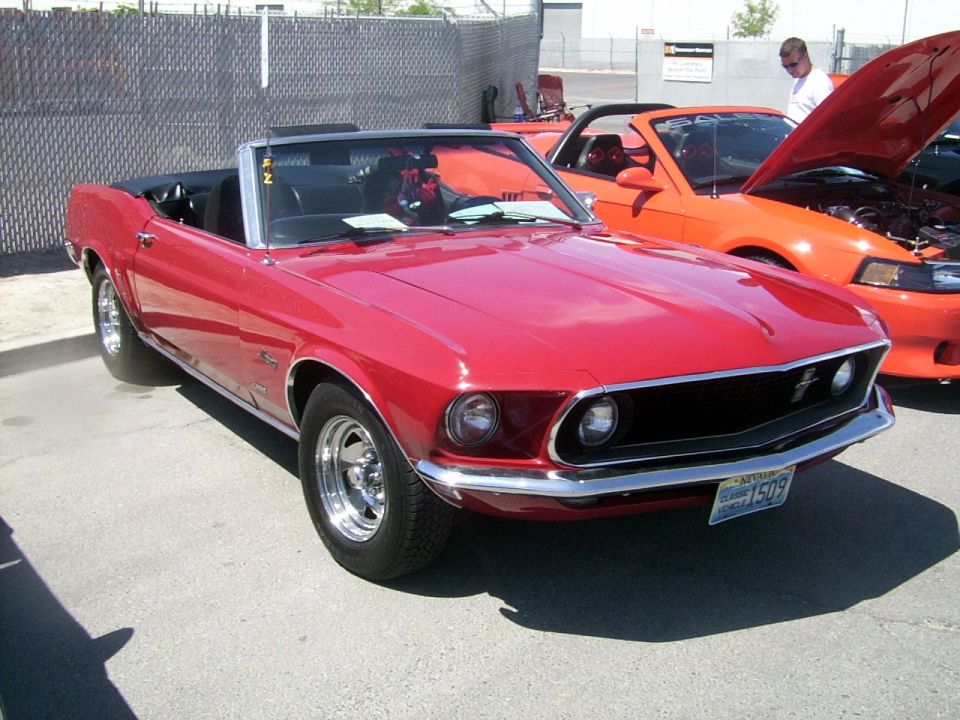 red convertible classic car parked next to an orange modern car