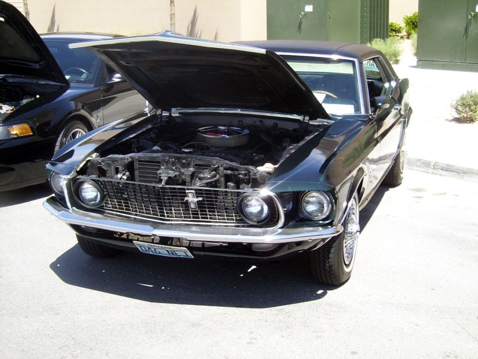 1969 Ford Mustang with hood open, parked next to a newer black car