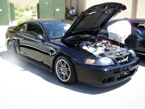 2002 Ford Mustang - A black 2002 Ford Mustang coupe is parked with its hood open, revealing the engine bay.