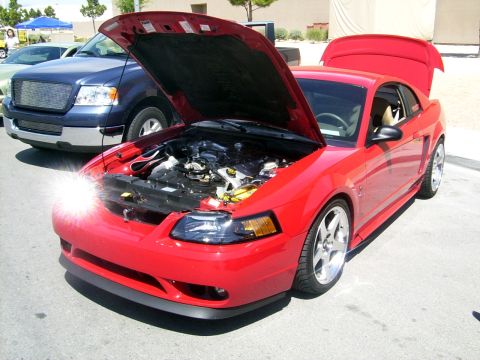 2002 Ford Mustang - A red 2002 Ford Mustang is parked with its hood and trunk open, revealing the engine bay.