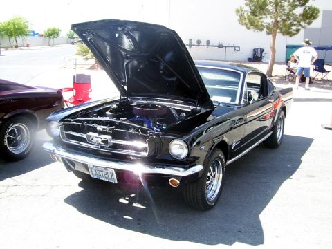 2002 Ford Mustang - A black 1965 Ford Mustang coupe is parked with its hood open, revealing the engine bay.
