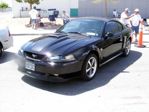 2002 Ford Mustang - Black 2002 Ford Mustang coupe parked outdoors with people in the background.