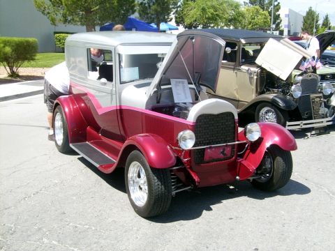 2002 Ford Mustang - A custom hot rod with its hood open is displayed at an event, with another vintage vehicle visible behind it.