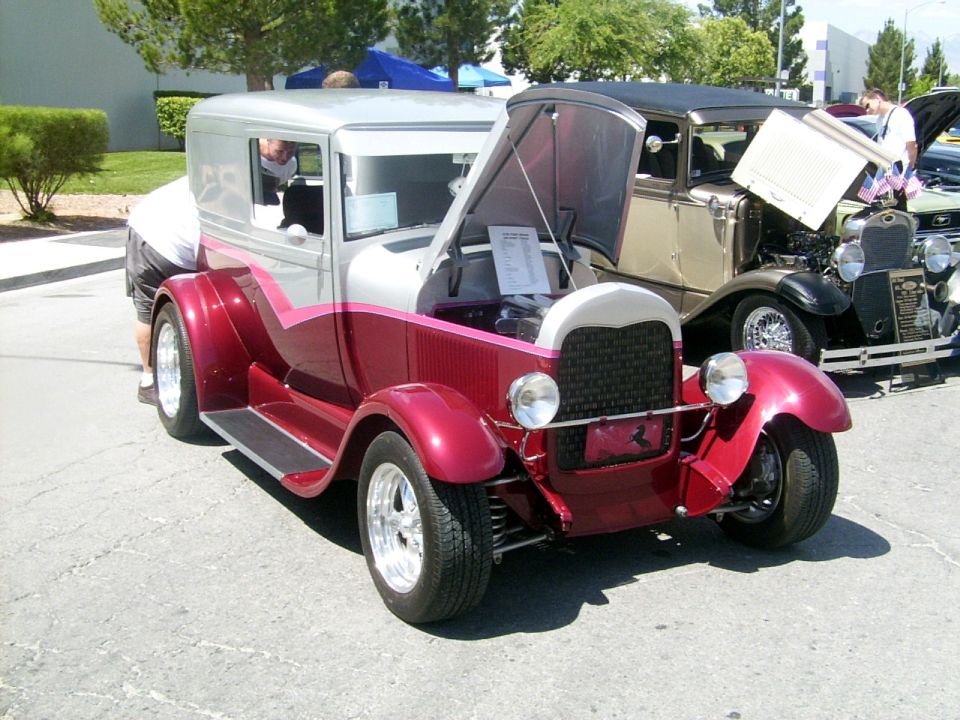 Red and silver hot rod with hood open, showing engine and a document