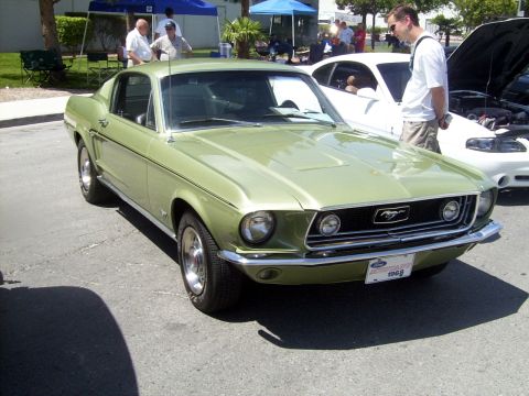 2002 Ford Mustang - A classic green Mustang is parked at an outdoor event with other vehicles and people around.