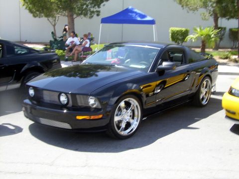 2002 Ford Mustang - Black Ford Mustang with custom wheels at an outdoor event.