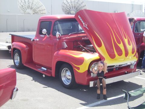 2002 Ford Mustang - A red 1956 Ford F-100 pickup truck with custom flame paint on the hood is displayed with its hood open.