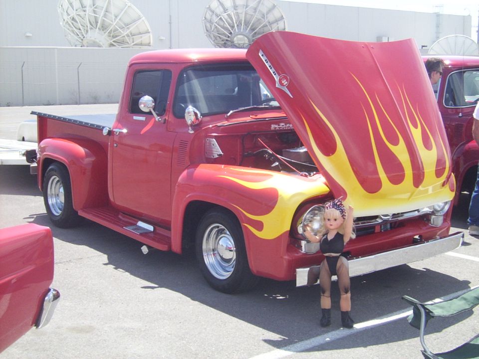 Red 1956 Ford F-100 pickup truck with yellow flames on hood, hood open