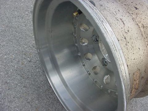1995 Ford Bronco - A close-up view of a worn metal wheel, showing its construction and bolt pattern.