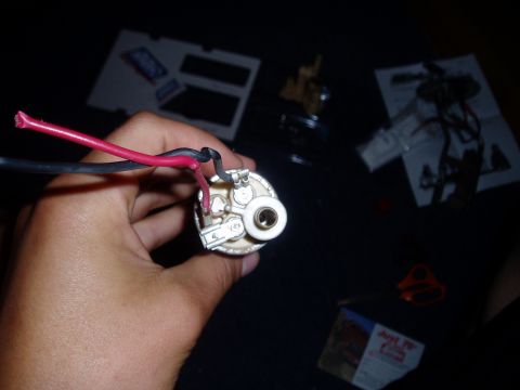 1990 Ford Bronco - A hand holds a fuel pump with attached wires, with various papers and tools scattered in the background.