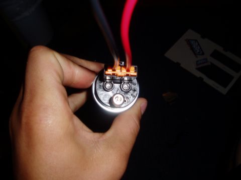 1990 Ford Bronco - A hand holds a fuel pump with wires connected to its terminal. A Supermotors.net watermark is visible.
