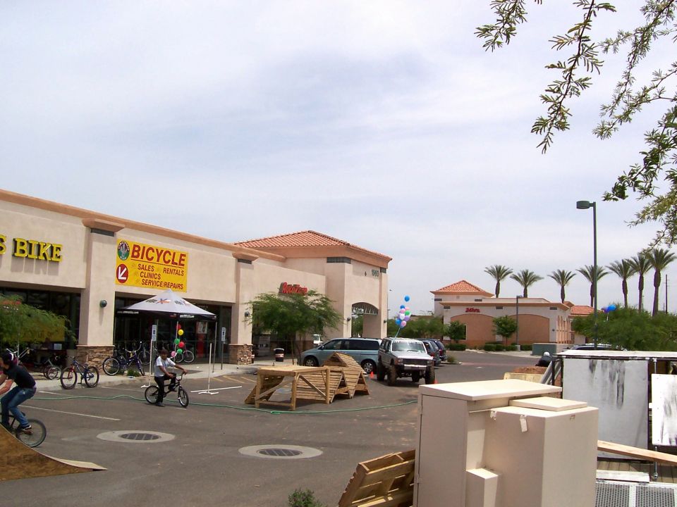 People riding bikes near a bicycle shop with ramps set up