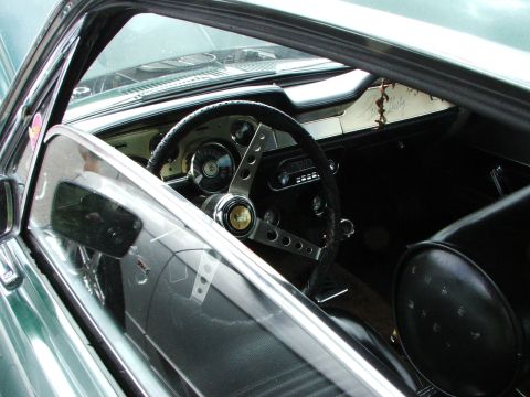 2005 Ford Mustang - The interior of a classic car is visible through the open window, a vintage steering wheel and dashboard.