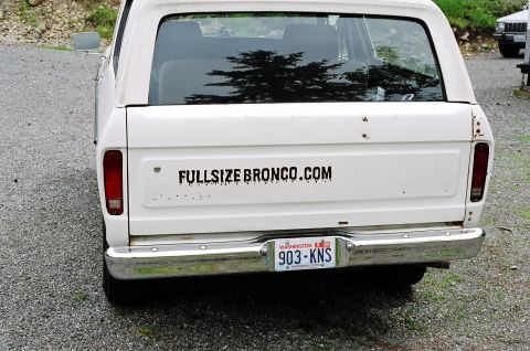 1979 Ford Bronco - Rear view of a white Ford Bronco, identified by its body style as a 1978 model, with a website sticker on the tailgate.
