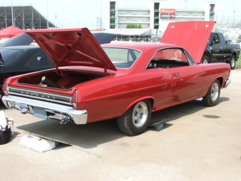 2005 Ford Mustang - A red 1966 Mercury Cyclone coupe is parked with its hoods open, showing its interior and engine bay.
