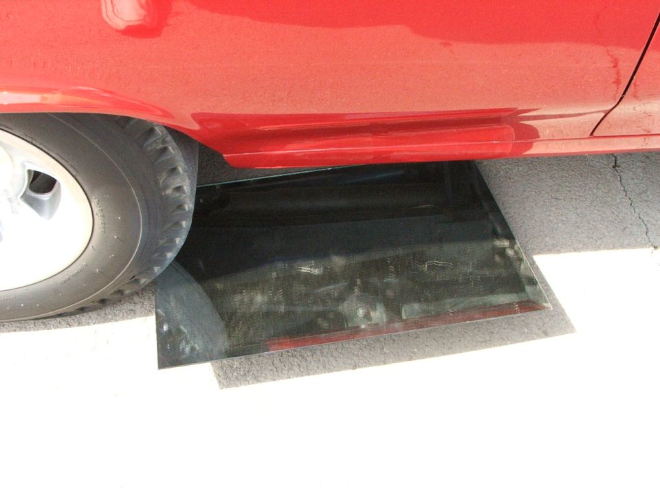 Red car side panel with a broken window piece on the ground