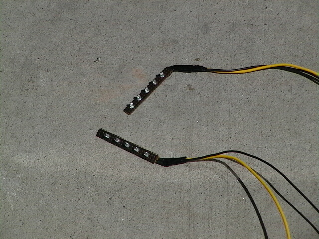 Two LED light strips with yellow and black wires on concrete