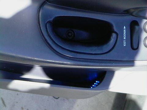 1999 Ford Taurus - Close-up of a car's interior door panel, showing the window lock button and illuminated blue LEDs.