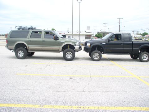 2000 Ford Excursion - Two lifted trucks, a Ford Excursion and an F-250, parked side-by-side in a parking lot.