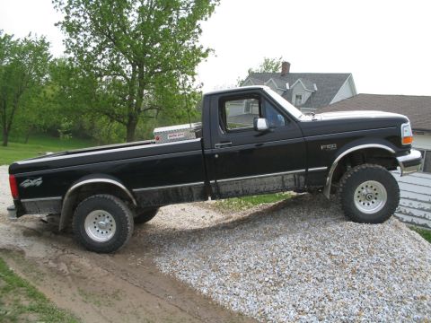 1979 Ford F-150 - This black Ford F-150 pickup truck is shown from the side, parked on a gravel incline.