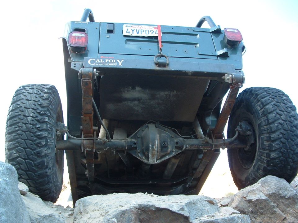 Underside rear view of a Cal Poly buggy showing axle and leaf springs over rocks