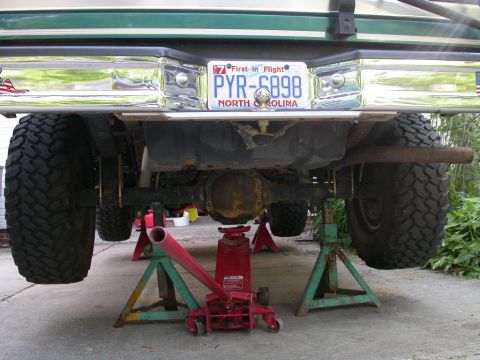 1996 Ford Bronco - Underside view of a lifted truck's rear axle and suspension, supported by jack stands.