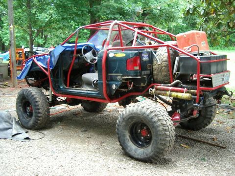 1985 Ford Bronco - This heavily modified off-road vehicle features a prominent red roll cage and oversized tires for extreme terrain.
