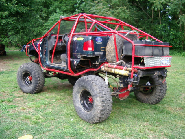 Modified off-road vehicle with red roll cage, large tires, and external fuel tanks