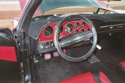 1972 Ford Ranchero - The interior of a car features a dashboard with multiple gauges and a steering wheel, accented with red trim.