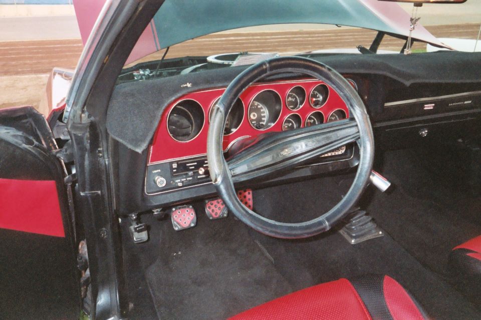 Ford Ranchero interior with red-black dash, round gauges, and steering wheel