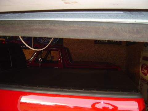 1978 Ford Bronco - A red pickup truck, possibly from the 1970s, is parked inside a garage or trailer.